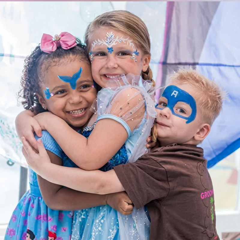 Três crianças sorrindo abraçadas com pintura facial de Frozen e super-herói em festa infantil, fotografia Pirralhitus no Rio de Janeiro